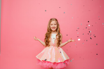 Obraz na płótnie Canvas happy Little girl catches confetti on pink background, holiday concept