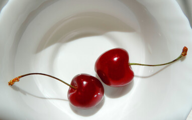    two raw cherries in a white dessert rosette      