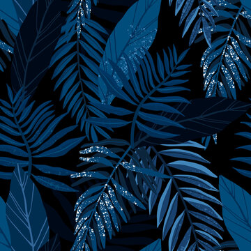 Seamless hand drawn tropical vector pattern with exotic palm leaves and various plants on dark blue indigo background.