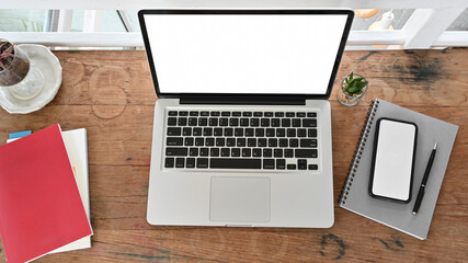 Workspace with laptop computer, smartphone, notebook, blank screen on wooden table. Top view