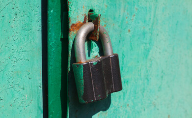 Iron lock hanging on a painted green door