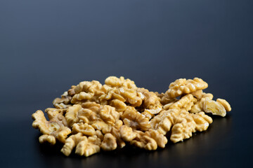 Peeled walnuts in halves on black background