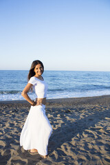 Fototapeta na wymiar Woman dressed in white barefoot on the beach sand