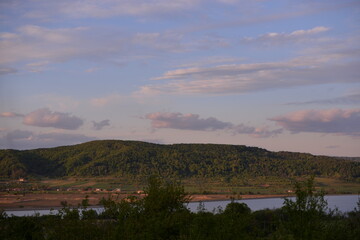 landscape with forest and lake. houses located near a field ready for cultivation