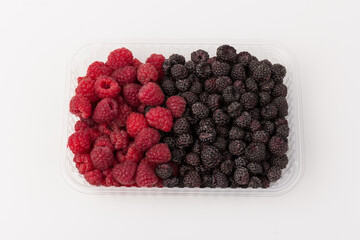 Fresh black and red raspberry in  plastic container isolated on white background. Berry in close-up