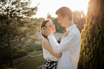 The young couple walking in the park. Couple hug. Man hug woman. Girl and boy on nature. On the sunset. Couple in love