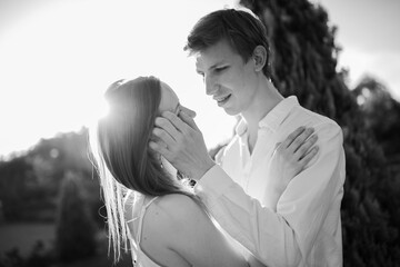 The young couple walking in the park. Couple hug. Man hug woman. Girl and boy on nature. On the sunset