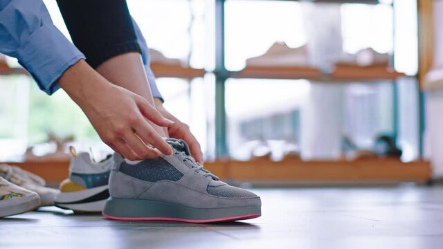 In a luminous shoe shop a lady take a sit on the sofa and try to wear new pair of sport shoes