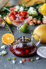 Glass teapot with fruit raspberry tea and mint on a blue background with fruits and decorations