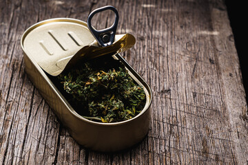 cannabis in a tin can. on old wooden background. rustic