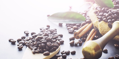 Coffee beans with green leaves for cooking. Bag of coffee. Coffee beans roasted on the table.