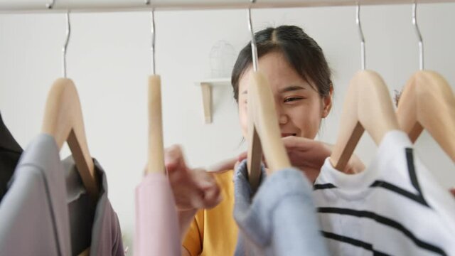 Young Asian woman choose clothes in the bedroom at home.
