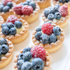 close up of fresh berry tarts with powdered sugar sweet pastries wedding favors party food