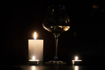 Candles and a glass of wine in the dark.