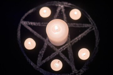 Pentagram and burning candles. The magical ritual of Satanism, invocation of spirits,...