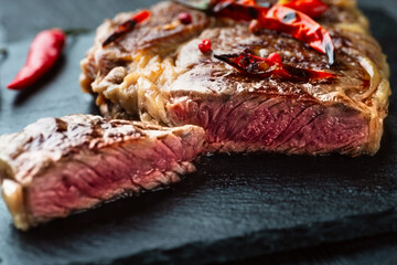 Sliced grilled meat barbecue steak Striploin with knife and fork carving set on black stone slate