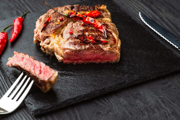 Sliced grilled meat barbecue steak Striploin with knife and fork carving set on black stone slate