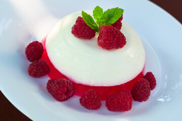 Panacota with raspberries on a white plate.
Close-up