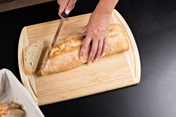 Beautiful woman cuts fresh bread on a wooden board, on a black table in a black dress. Different views