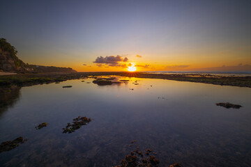 Seascape. Beach at sunset during low tide. Sunset golden hour. Bright sunlight reflection in water. Bingin beach, Bali, Indonesia