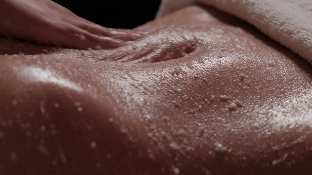 Cleansing massage for the body. Body scrub for clean skin. Masseur massages the stomach of a girl close-up.