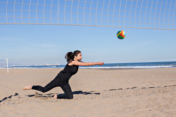 Beach volleyball, summer vacation, sport and people concept - young woman with ball playing volleyball on beach.