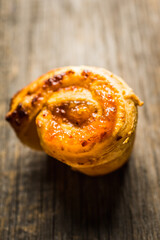 Fresh sweet bun with orange jam on the rustic wooden background. Selective focus. 