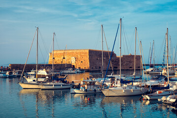 Venetian Fort castle in Heraklion and moored fishing boats, Crete Island, Greece on sunset
