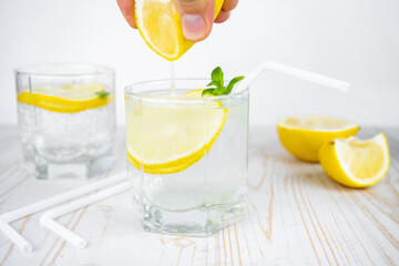add lemon juice in a glass of soda water with ice and mint. refreshing summer cocktail concept with tonic or transparent alcohol