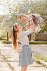 Obraz premium A young mother plays with a little girl outdoors in the summer. Mother and daughter
