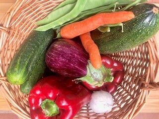 Cesta de mimbre con verduras frescas de la huerta: pimiento, pepino, berenjena, zanahorias, ajo, judias verdes. 