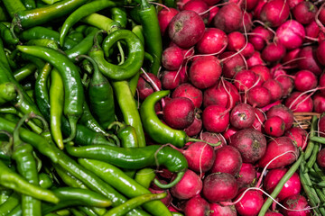 Red radish and hot chili peppers on market. Vegetables background.
