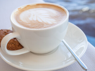 White coffee cup with a single cookie