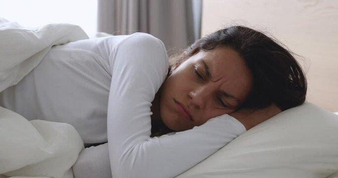 Frustrated upset young woman lying awake in bed alone trying to sleep suffer from insomnia or uncomfortable bad mattress, annoyed stressed lady insomniac feeling disturbed toss and turn in bedroom