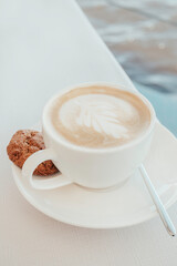 White coffee cup with a single cookie