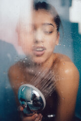 Beautiful woman behind the glass with water drops.