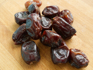 a handful of dates are scattered on a wooden surface. Useful sweets, diet, edible fruits of the date palm. High value food