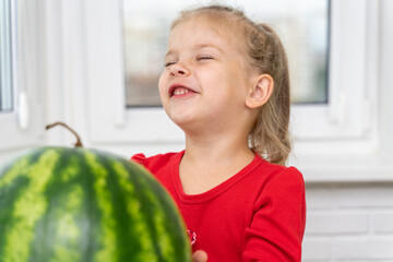 Fototapeta premium child is looking at a watermelon and smiles