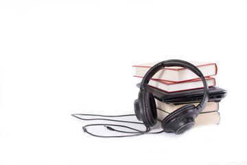 A stack of books with a laptop and headphones isolated on a white background