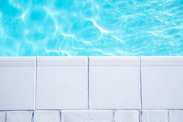 Empty swimming pool from a luxury house with white tiles around and clear transparent turquoise blue water. Real estate, property or hotel stylish pool