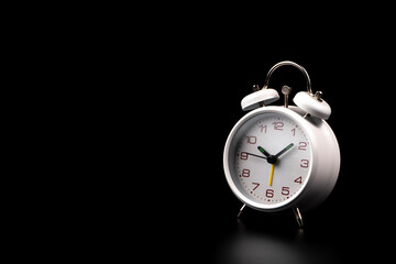 White alarm clock on black background.