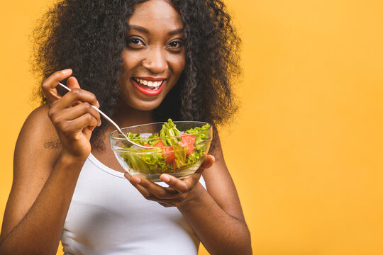 Healthy Food Concept. Close-up Of Beautiful African American Black Woman Eating Salad Isolated Over Yellow Background.