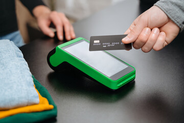 Closeup view, male customer using bank credit card for contactless payment by nfc terminal on...