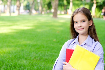 Fototapeta premium Back to school. Education concept. Cute smiling schoolgirl holding the books outdoor