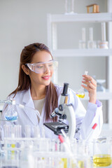 Young Asian scientist woman lab technical service holding flask with lab glassware and test tubes in chemical laboratory background, science laboratory research and development concept