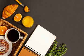 Obraz na płótnie Canvas Wicker basket with breakfast. Hot coffee, croissant, fresh pastries and orange juice on a black background