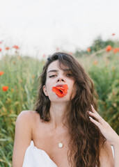 Girl wrapped in a blanket, with flowers. Stylish photo of a girl in a poppy field. Beautiful woman in a blanket in the field.