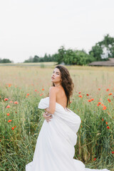 Girl wrapped in a blanket, with flowers. Stylish photo of a girl in a poppy field. Beautiful woman in a blanket in the field.