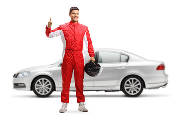 Car racer posing in front of a silver car and showing thumbs up