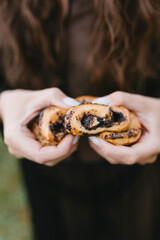 Woman holds a bun with poppy seeds in her hands in a poppy field